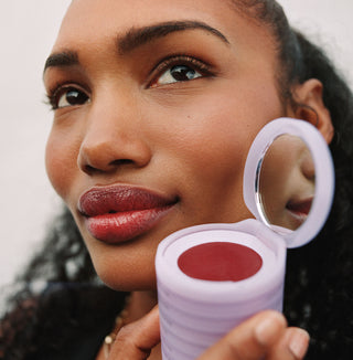 Woman posing with her makeup stack wearing a bright lip color
